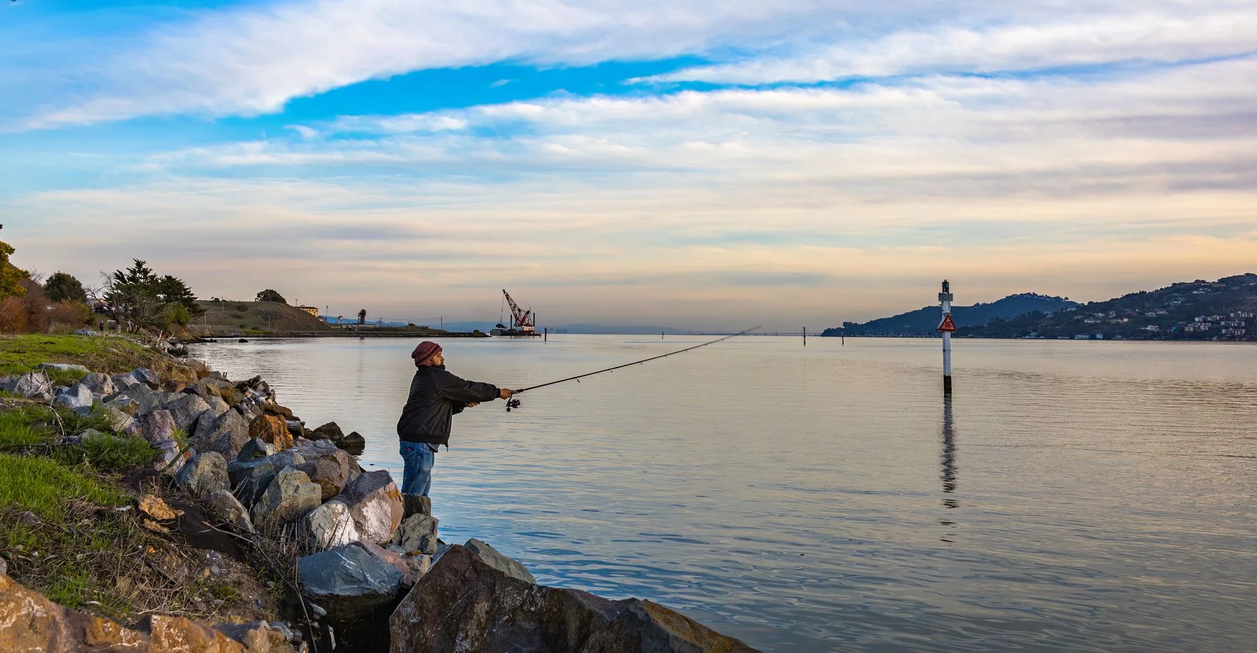 Angler beside a lake under a cloudy sky