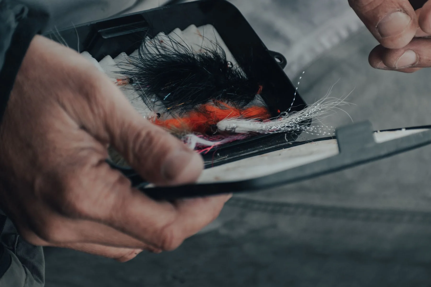 Hands selecting a spinner from a tackle box